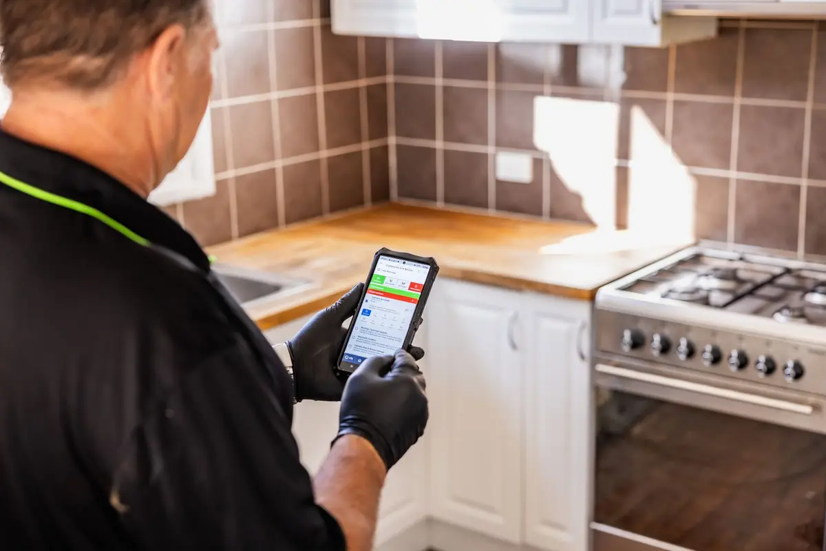 Inspector recording kitchen cupboard findings on a phone checklist during a building inspection in WA