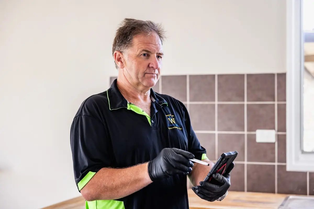 Building inspector reviewing inspection notes on a phone during a property inspection in WA