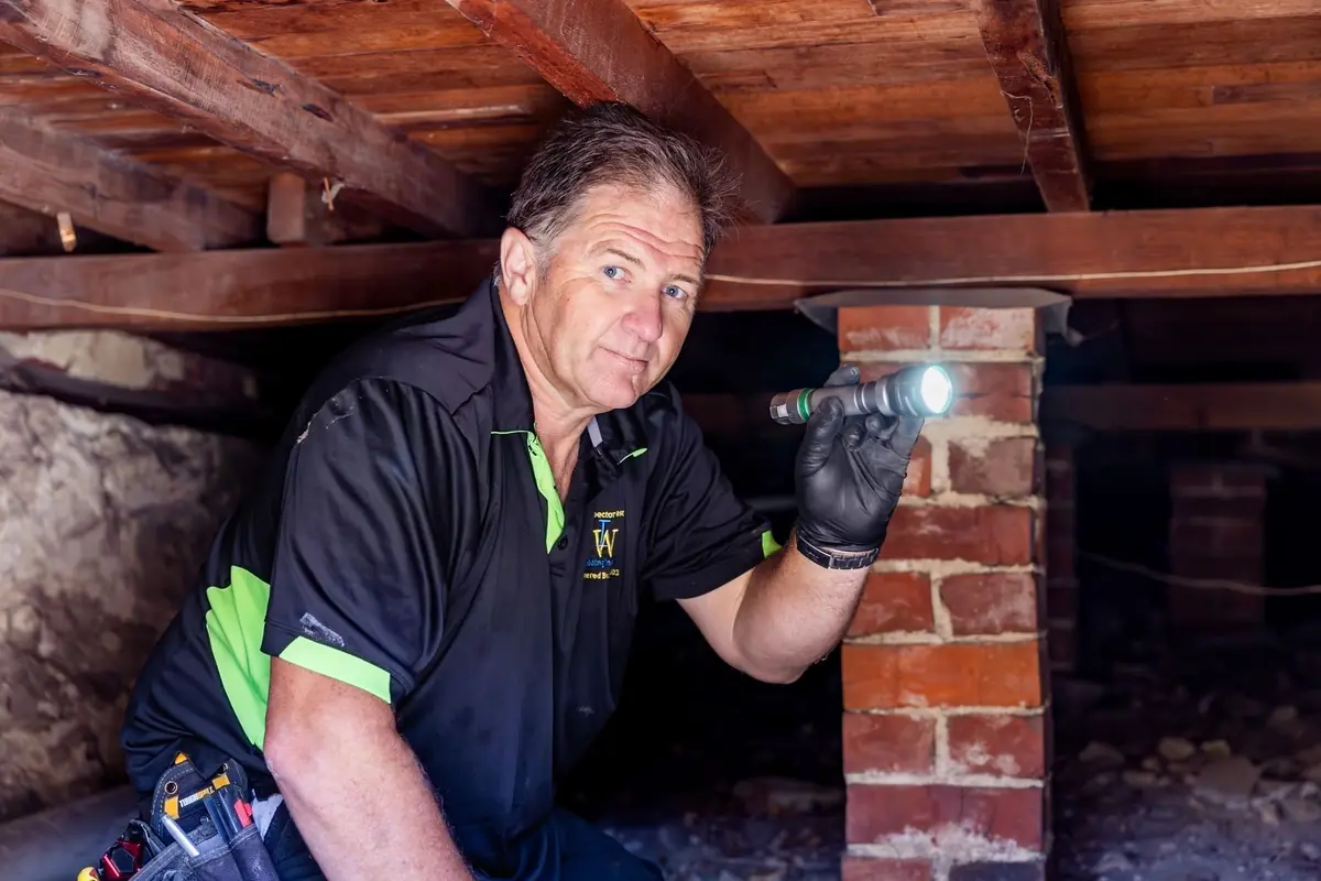 Inspector checking a brick pier in the subfloor during a building inspection in Perth